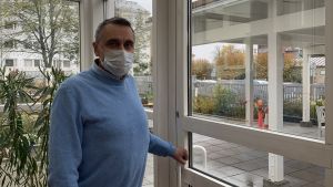 Peter Guss, föreståndare på äldreboendet Fylgia i Vasa, säger att det är svårt att fatta beslut som begränsar eller stoppar besök. Samtidigt känns det självklart att skydda liv och hälsa. Man i ljusblå tröja och vitt munskydd öppnar dörren från inglasat uterum till trädgård utanför.