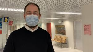 Rektor Markus Rönnblom är tacksam över att man kunnat ha närundervisning nästan hela höstterminen. Till våren drömmer han om lättare restriktioner och att kunna öppna upp skolan som normalt gentemot samhället igen. Mansperson står i skolkorridor, bär munskydd.