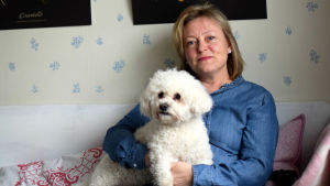 Tina Landén är i dag mera medveten om genusfrågor och vill förändra sitt sätt att arbeta så att alla barn behandlas jämlikt. Tina Landén sitter i en träsoffa med hunden Knut i famnen.