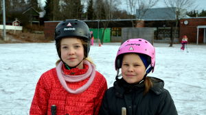 Två skolflickor med ishockeyhjälmar på huvudet.