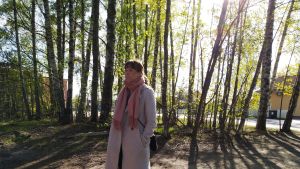 Annika Pottonen har bott fem år i Mosabacka. Hon är orolig för att bykänslan kommer att försvinna i och med den nya detaljplanen. En kvinna som bor i Mosabacka står och lyssnar på en diskussion. Solen skiner mellan träden bakom henne.