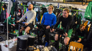 Andreas Flinck, Rolf Larsson och lagkaptenen Ville-Veikko Angeria värmer upp inför den sista träningen. Uppvärmning i omklädningsrummet med konditionscykel.