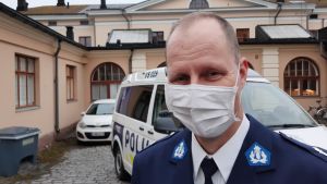 Fred Lindblom säger att de håller standarden hög och att den interna granskningen är hård, då vi frågade om hur han tänker kring de skandaler som uppkommit i samband med polisen på sistone. Fred Lindblom, en man med tunt ljust hår, vitt munskydd och polisuniform, står framför en polisbil.