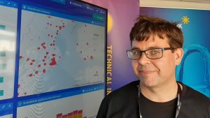 Jani Enqvist, lektor vid Åbo Yrkeshögskola, står framför en karta som visar var det skett cyberangrepp i Sverige och Finland under den senaste veckan. ekqvist tittar in i kameran.