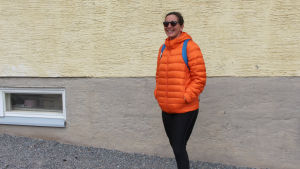 Piia Tamminen väntar i kön vid Kyrkfjärdens skola. kvinna i orange jacka