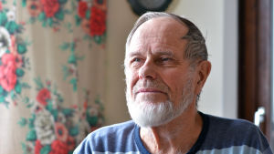 Harold Henriksson, ordförande för Åbolands synskadade rf. Porträtt på en man som tittar snett ut genom fönstret.