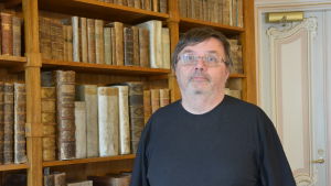Professor Antti Laato i Teologicum vid Åbo Akademi. Professor Antti Laato framför en bokhylla i Teologicum.