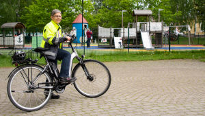 Mirjam Manninen rör sig lätt från park till park med hjälp av stadens elcykel. Mirjam Manninen står med sin elcykel utanför Muminparken.