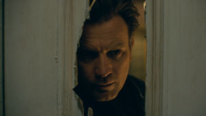 Dan (Ewan McGregor) trodde han lämnat de traumatiska händelserna i barndomen bakom sig. Närbild på Danny (Ewan McGregor) då han tittar in genom ett hål som hackats upp med yxa i en dörr.