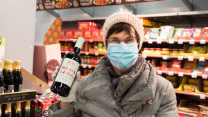 Lisbeth Salminen handlar glögg som släktingarna serveras på balkongen. En kvinna står med en glöggflaska i handen i en butik.