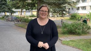 Mia Henriksson anser att det beror väldigt mycket på sällskapet när hon väljer språk. Mia Henriksson, en kvinna i svart tunika, står på sin innergård.