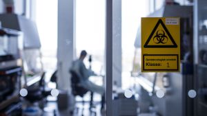 Ett vaccin mot det aktuella coronaviruset skulle bli det första i världen som tillverkats med hjälp av genteknologiska metoder. En varningsskylt på en glasvägg vid Köpenhamns universitet varnar för gentekologiskt område.