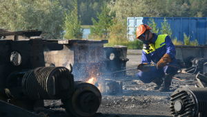 De sovjetiska maskindelarna består av tjocka järndelar. De tar tid att bränna sönder. Man med ansiktsmask och skyddhjälm som bränner sönder metall med ett svetsliknande verktyg.