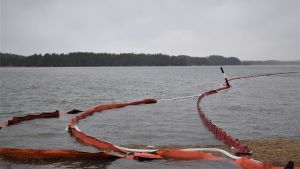 Oljebekämpningsarbetet fortsätter åtminstone till slutet av våren. Röda bommar som ska hindra oljan från att sprida sig i vattnet. De vita bommarna suger upp oljan.