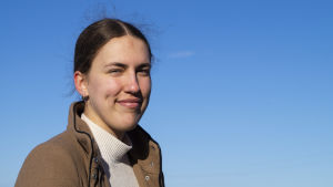 Snart sommar. Amanda Rönnblom drömmer om att få träffa vänner, sitta i solen och känna sig stressfri. Ung kvinna kisar mot solen, omgärdad av blå himmel.