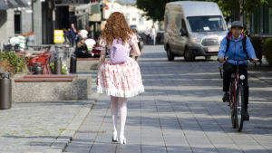 Gulliga accessoarer som ryggsäcker med öron på, hör till stilen sweet Lolita. En kvinna klädd i så kallade Lolitakläder - en fluffig vit och rosa klänning med spetsar på. Hon har vita högklackade skor, blommor i håret och en lila ryggsäck med kaninöron på. Vi ser henne bakifrån när hon går på en trottoar i centrum av Vasa.