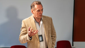 Kriminalkommissarie Hannu Kortelainen utreder bland annat romansbedrägerifall på Helsingforspolisen. Enheten för nätbedrägerier grundades 2016 då allt fler fall krävde specialiserade utredare. Polisen Hannu Kortelainen står civilklädd i ett mötesrum på polisstationen.