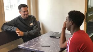 Martin Malmberg har under sin tid som rektor koncentrerat sig på att rekrytera bra lärare och skapa lugn i skolan. Rektorn Martin Malmberg diskuterar med en elev vid ett bord.