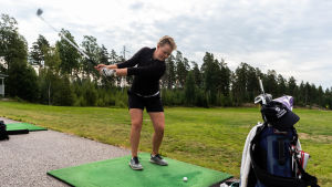Matilda Svahn är ute på golfbanan nästan varje dag. En kvinna står med klubban i luften, beredd att slå till en golfboll.