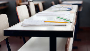 En pulpetrad med häften i ett klassrum.