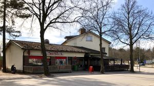 Lugnt både utanför och innanför Jan Rönnbergs pub och grill vid Kanaltorget i Karis. Ett hus vid en gata. Man ser en skylt ute på trottoaren, men inte vad det står. Vår och sol.