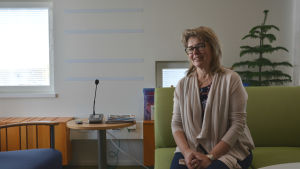 Rektor Ulrica Nyström ser fram emot att ta hela skolan i bruk i höst. Blond kvinna med glasögon på en grön soffa.
