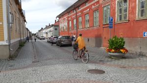 Raumo med sina medeltida byggnader och gatusystem finns med på Unescos världsarvslista. En cyklist med gul tröja cyklar på den stenlagda gatan mellan trähusen i Gamla Raumo.