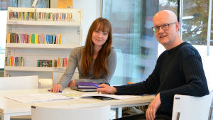 Linda Loimijoki och Janne Lahtia hjälper unga som är på jakt efter ett sommarjobb. Linda Loimijoki och Janne Lahtia sitter vid ett bord i ett ljust bibliotek.
