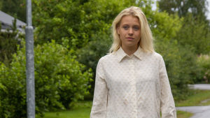 Alva Nygård ger ut låtar under artistnamnet Alva Elle. En ung kvinna med blont hår och vit skjorta går på en gata. I bakgrunden syns gröna löv. Det är sommar.