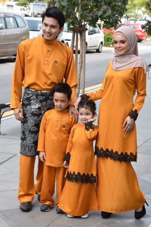 Modeller poserar för en fotograf som en perfekt muslimsk familj. Flickorna börjar vanligen täcka sitt hår när de kommer upp i skolåldern. En muslimsk familj poserar för en kamera klädda i oranget med påklistrade leenden.