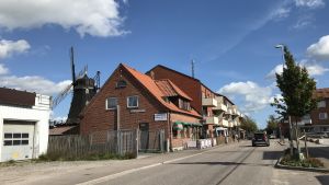 Den lilla gatan med affärer och några restauranger börjar vid kvarnen och går ner till Stora torget. Gammal väderkvarn och nyare tegelhus vid en smal gata.