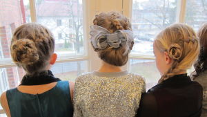 Flickor på balen år 2013. tre flickor står med ryggen till, de har flätade festfrisyrer.