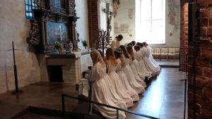 Social distans under sommarens konfirmationer utmanar församlingarna. Ungdomar i vita kåpor knäböjer och får nattvarden då de konfirmerats i Pargas kyrka.