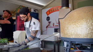 – Att det inte finns rinnande vatten i båsen kan vara knepigt ibland, men vi har varit väldigt nöjda överlag, säger Julia Kokki. På bilden syns pizzakocken Marco. Pizzakocken Marco lagar pizza på Senatstorget.
