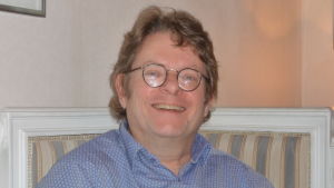 Robert idag. Skägg odlar han inte. Ärren och groparna gör att skägget växer ojämnt. Robert Harling sitter i soffan, skrattar och ser glad ut.