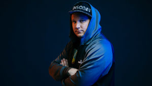 Benjamin Särkkä medverkar i den väldigt konkreta och ögonöppnande serien Team Whack som finns på Yle Arenan, där han och två andra hackers visar att nästan all teknik i vårt samhälle går att hacka. Kuvassa Benjamin Särkkä, tietoturva-alan asiantuntija ja hakkeri. Neutraali keskittynyt ilme, kädet puuskassa ja katsoo kameraan.