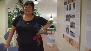 Agneta Möller-Salmela brinner för att lära barn och unga att tycka om läsning och böcker En kvinna i svart klänning ler mot kameran. Hon står i en utställningshall i ett bibliotek (Hangö)