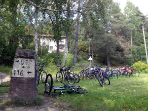 Klinkbackaeleverna flyttar enligt förslaget till Kiilan koulu. Inflyttningen till Raseborg kan rubba den planerade besparingen. Cyklar utanför en byskola, grönt gräs, i förgrunden en gammal milstolpe.