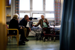 Tre personer sitter i sjukhusrum.