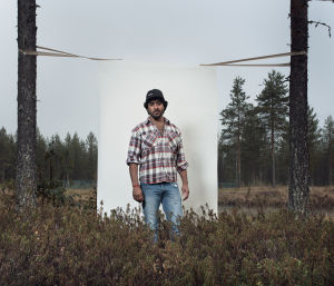 Irakilainen nuori mies, Saif, seisoo valkokankaan edessä suolla mäntyjen välissä.