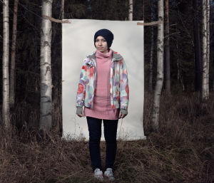 Irakilainen turvapaikanhakijatyttö, Sams, seisoo valkokankaan edessä koivumetsässä.
