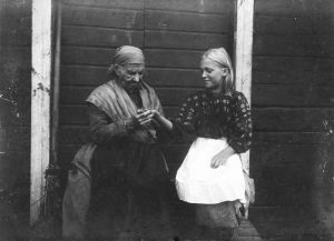 Anni-Pulkki povaa nuoren tytön kädestä Paiholassa vuonna 1911. Anni-Pulkki, vanha eukko, povaa nuoren tytön kädestä.