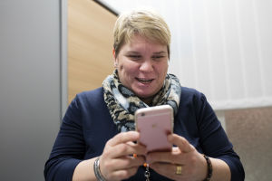 Katja Kuusela esittelee hymyillen älypuhelimensa ominaisuuksia.