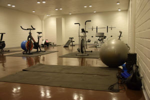 Ett gym med gymnastikmattor på golvet, motionsscyklar och andra motionsredskap.