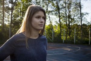 Ung kvinna med långt brunt hår och blå tröja fotad i profil.