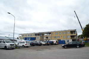 Bilar parkerade framför ett hus som håller på att byggas.
