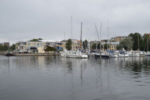 En småbåtshamn med segelbåtar. I bakgrunden skymtar ett nybyggt flervåningshus.
