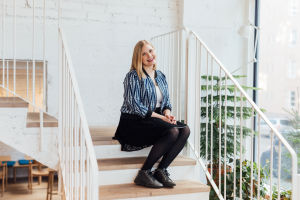Michaela von Kügelgen ska kanske vara med igen nästa år. Michaela von Kugelgen sitter i en trappa. Väggen bakom är vit och trappan är också vit, med trappräcke av metall. Hon har på sig en svart kjol och en blåspräcklig jacka.