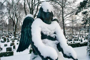 Lumi on peittänyt enkelipatsaan kasvot Hietaniemen hautausmaalla.