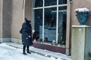 Nainen kynttilä kädessään Hietaniemen hautausmaan kolumbaarion edessä.